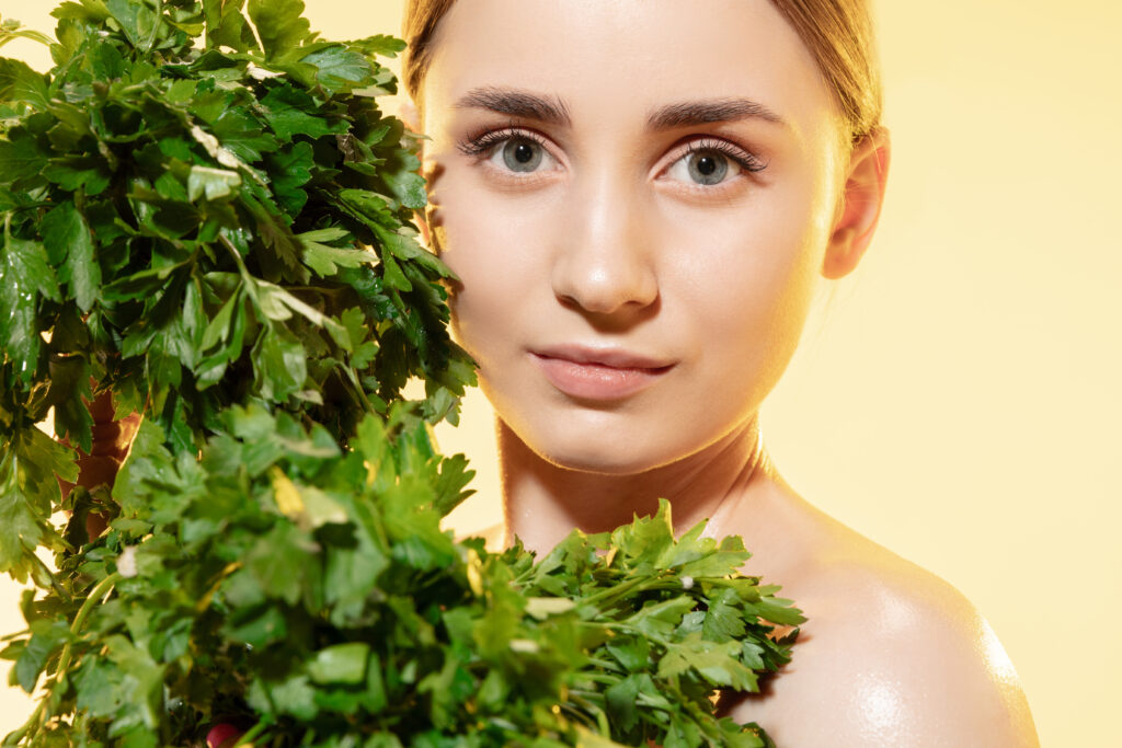 Mujer joven y guapa con hojas verdes una planta