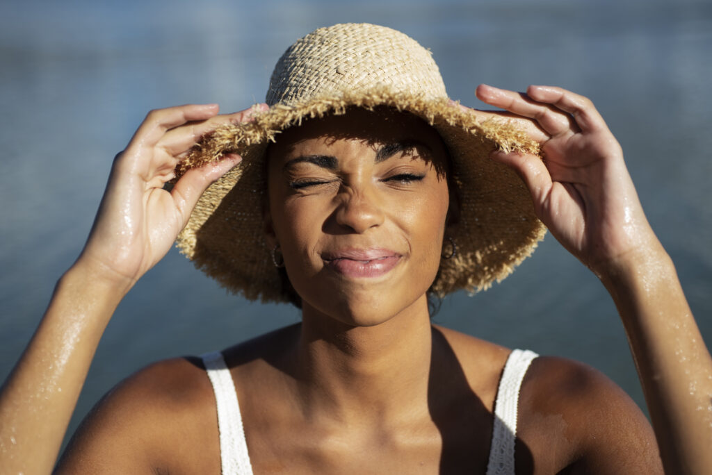 mujer sonriendo frente al sol con sombrero de paja